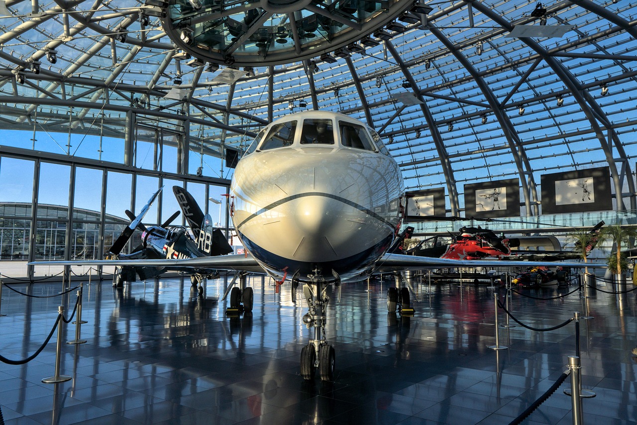 Vintage and modern aircraft displayed inside a glass-domed aviation museum hangar