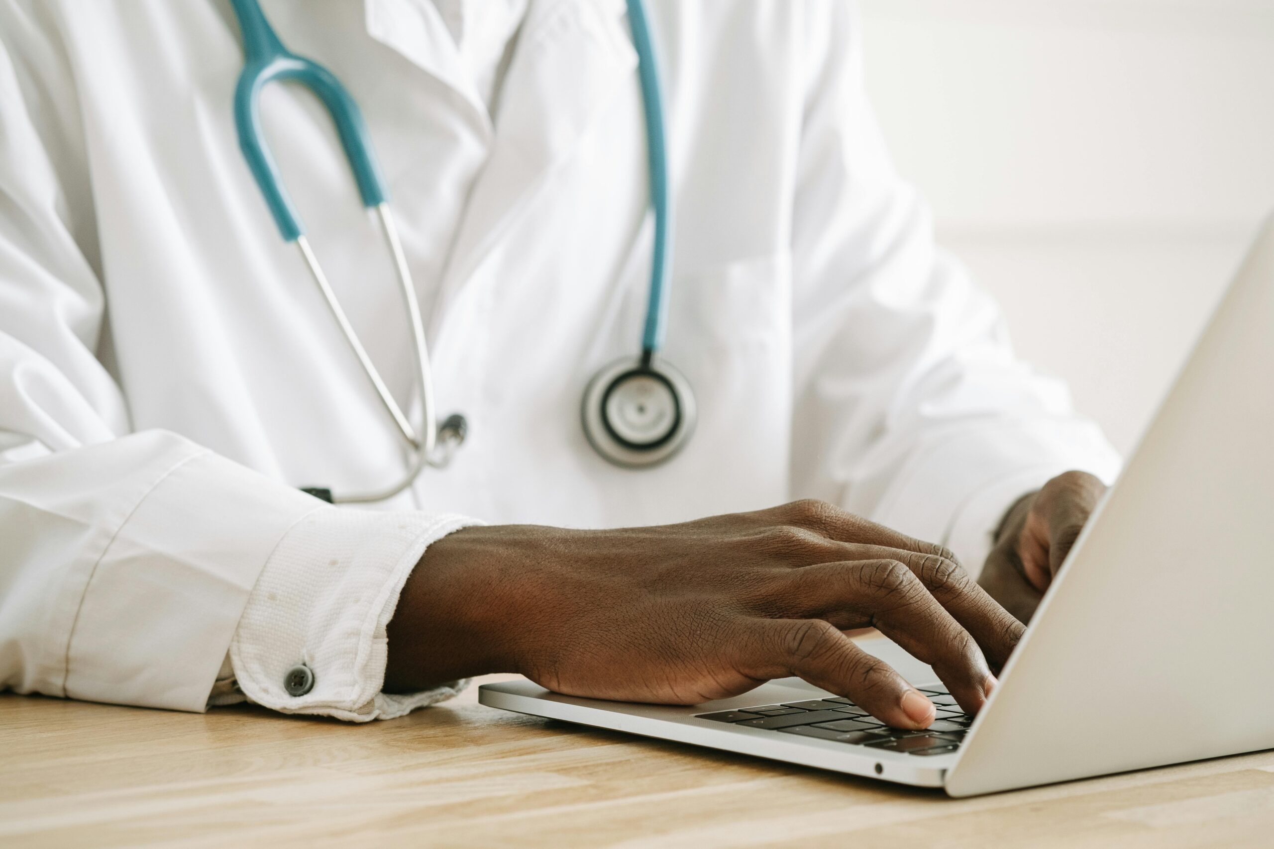 Black healthcare professional typing on a laptop with a stethoscope &mdash; symbolizing diversity in kidney research through the Kidney Foundation&rsquo;s KRESCENT program.