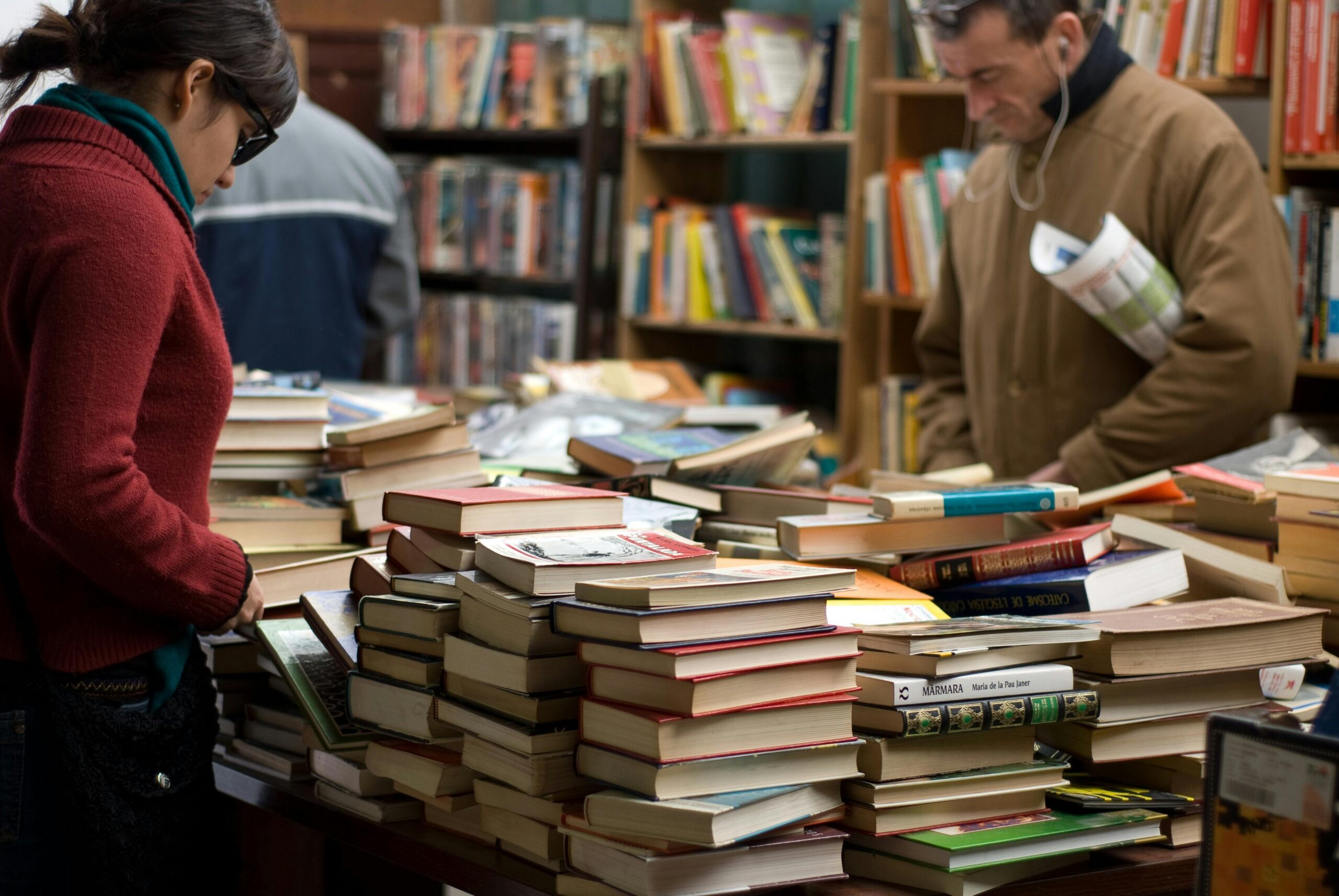 People browsing stacks of used books at a charity book sale hosted by a nonprofit organization in Calgary, Alberta.