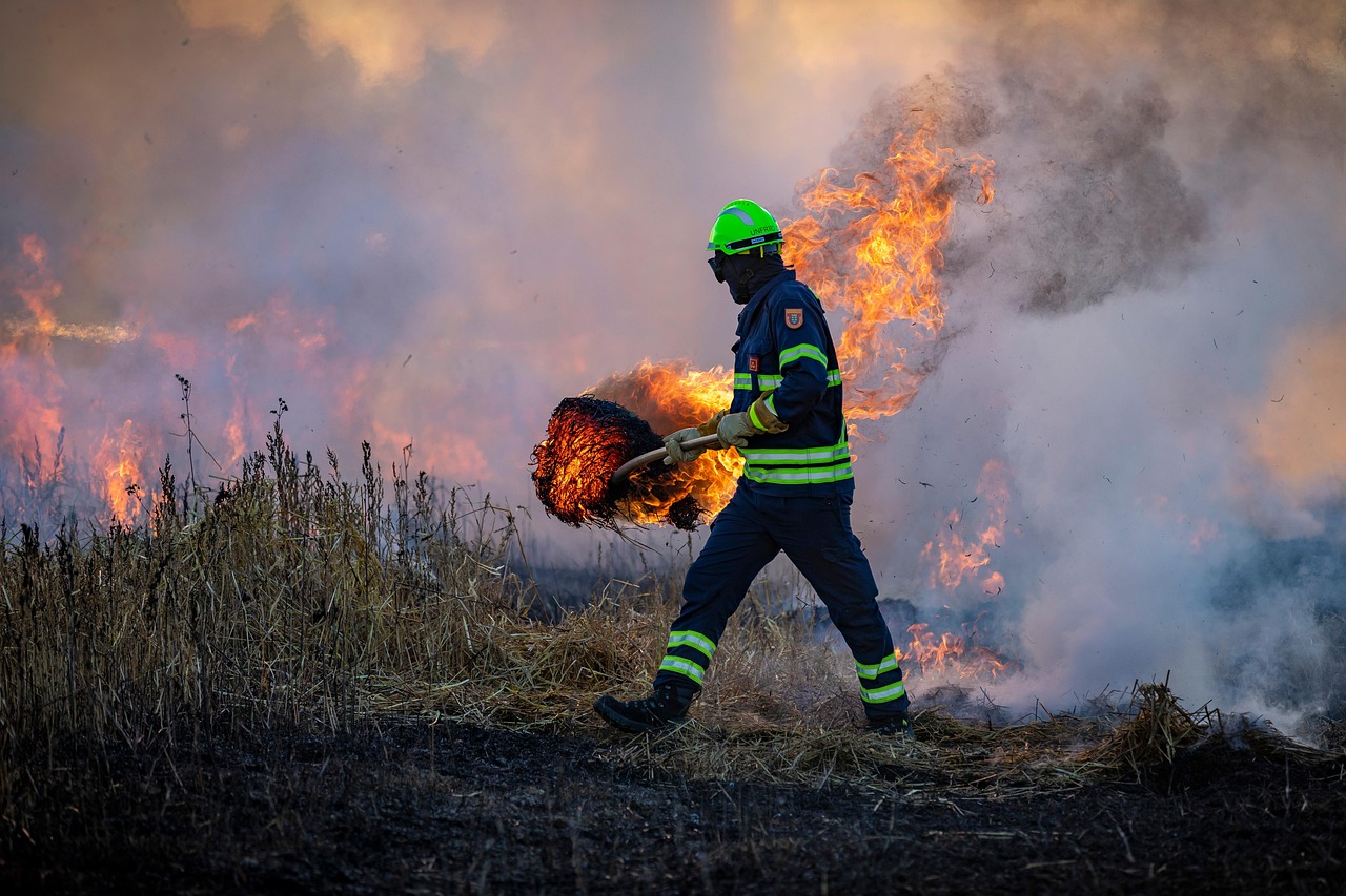 Firefighter tackling a wildfire in dry grasslands, reflecting the urgent need for charities in Canada like the Red Cross to support survivors in Newfoundland and Labrador.